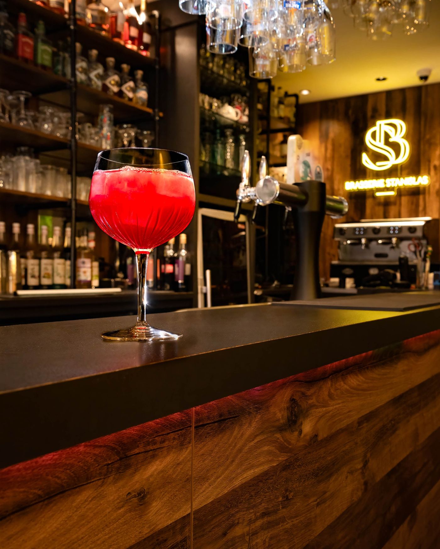Cocktail servi au comptoir du bar sous l'enseigne lumineuse Brasserie Stanislas